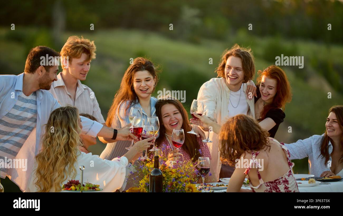 Grand groupe d'amis partageant un rire spontané pendant un repas en plein air Banque D'Images