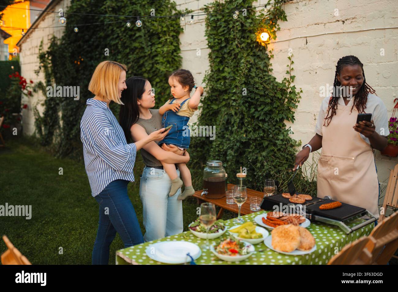 Amis multiethniques profitant d'une fête barbecue dans le jardin avec un bébé Banque D'Images