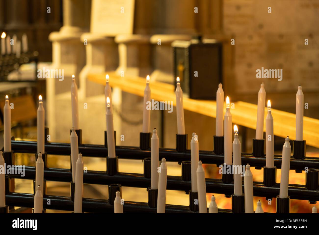 Rangées de bougies de prière blanches brûlant à l'intérieur d'une église historique Banque D'Images