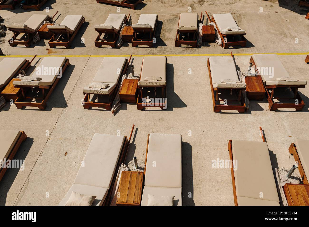 Disposition ordonnée de transats confortables sur une terrasse de station balnéaire. Cadre de vacances minimaliste préparé pour les invités d'été. Banque D'Images