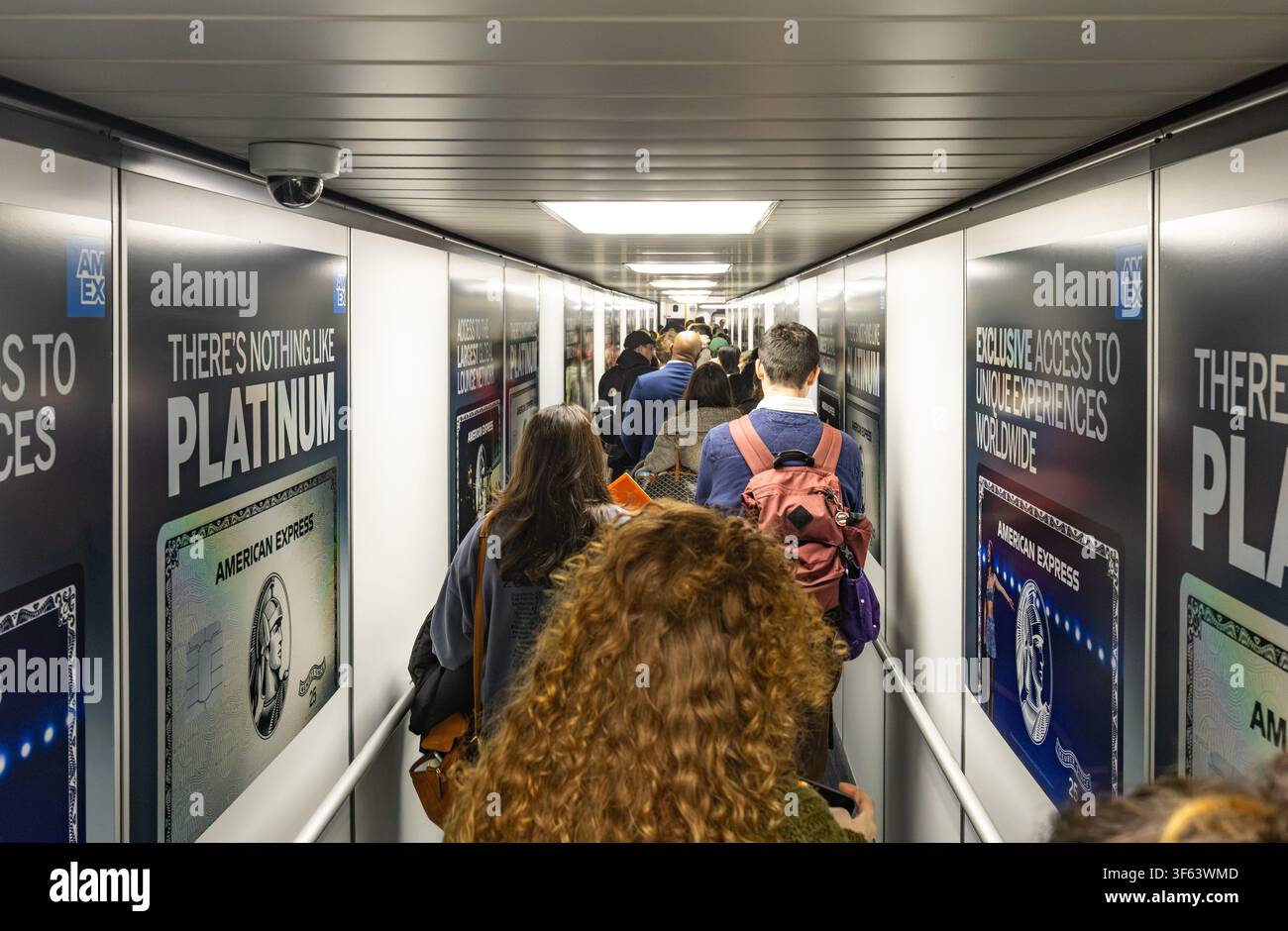 Paris, France - 5 juillet 2026 : Des passagers traversent une passerelle d'aéroport avec des publicités American Express Platinum pour embarquer dans un vol Banque D'Images