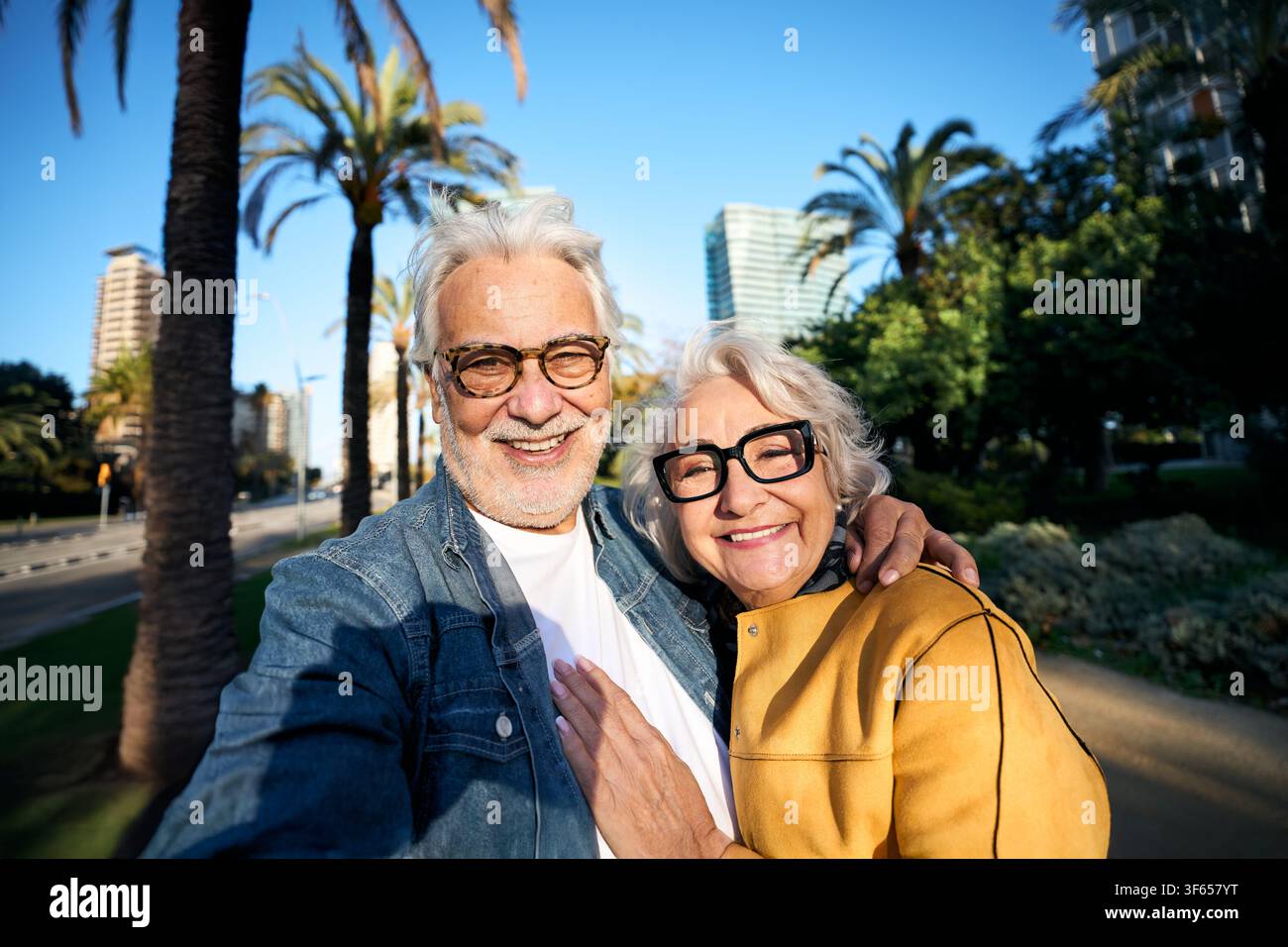 Couple de personnes âgées heureux prenant un selfie ensemble dans un parc urbain ensoleillé Banque D'Images