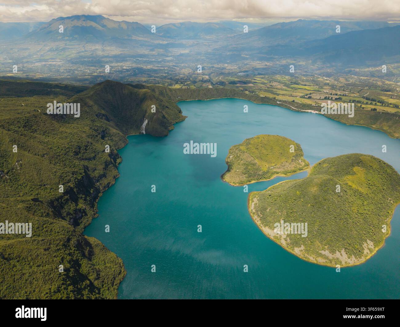 Vue aérienne de la Laguna de Cuicocha avec ses îles, entourée de pentes volcaniques vertes luxuriantes et de chaînes de montagnes lointaines sous un ciel nuageux Cotacachi, Banque D'Images