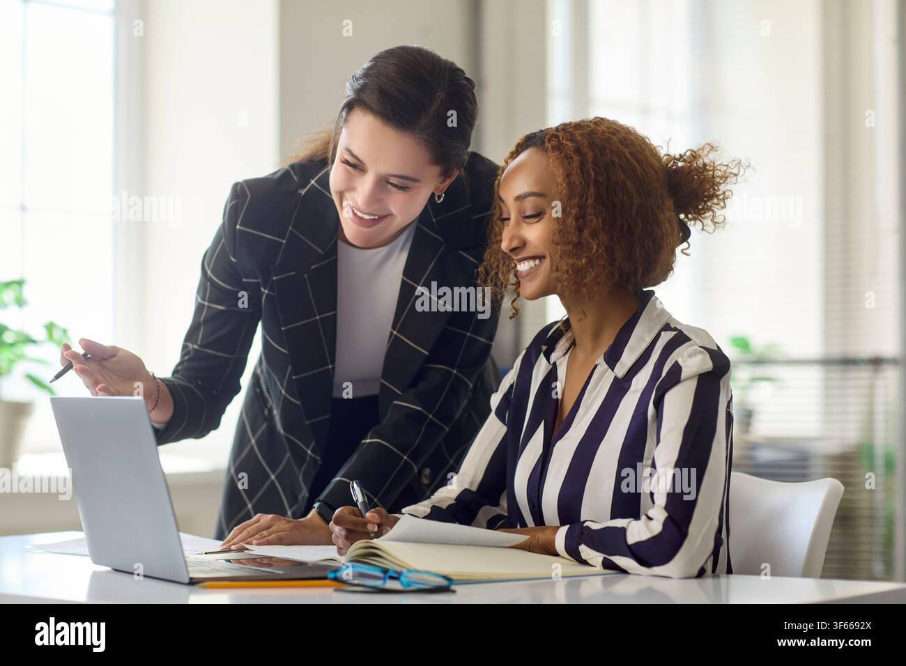 Deux femmes d'affaires collaborant sur un ordinateur portable dans un bureau moderne, travail d'équipe et planification Banque D'Images