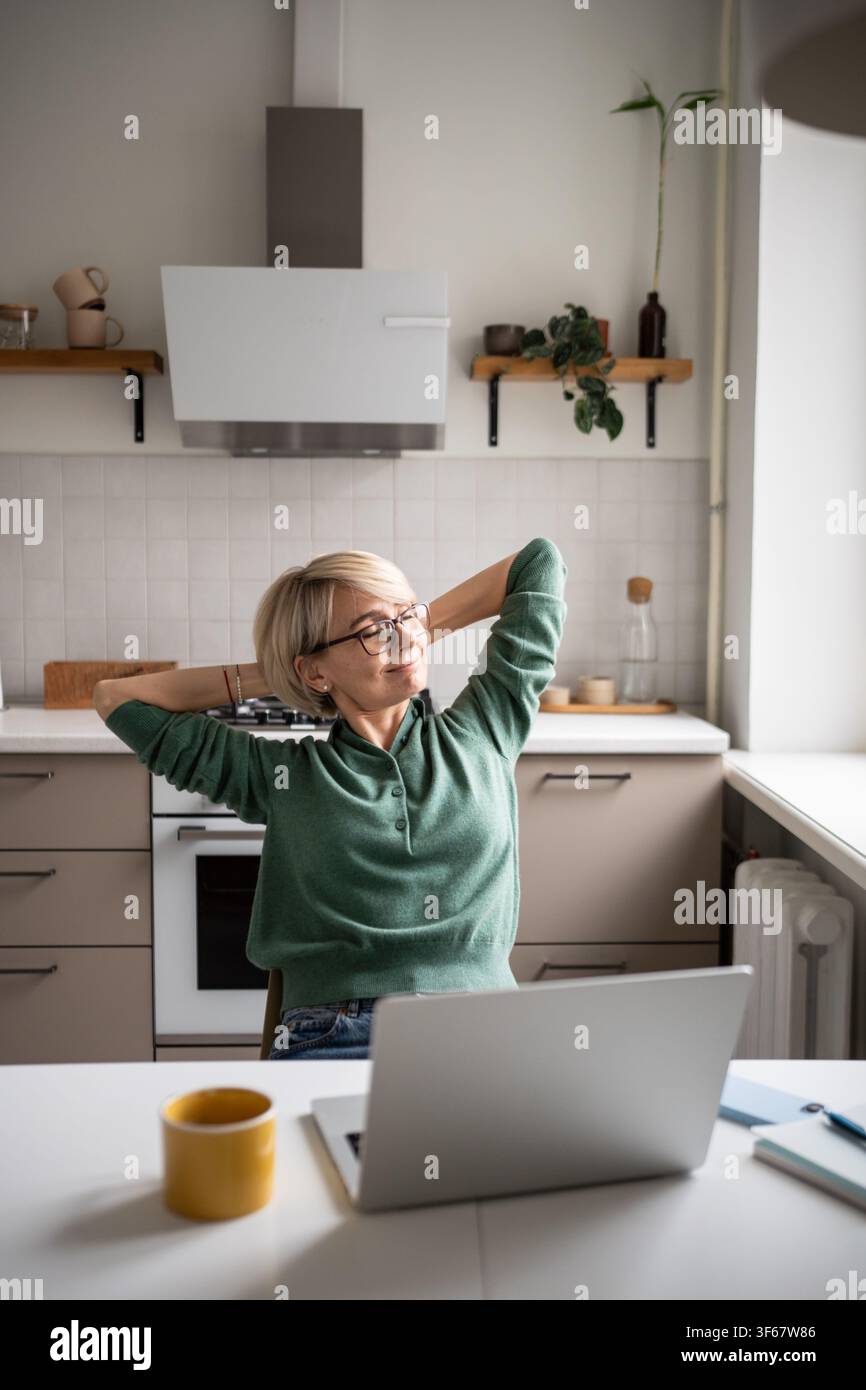 Femme d'affaires heureuse se reposant dans la chaise étirant les bras et souriant, satisfaite après avoir terminé les tâches. Banque D'Images