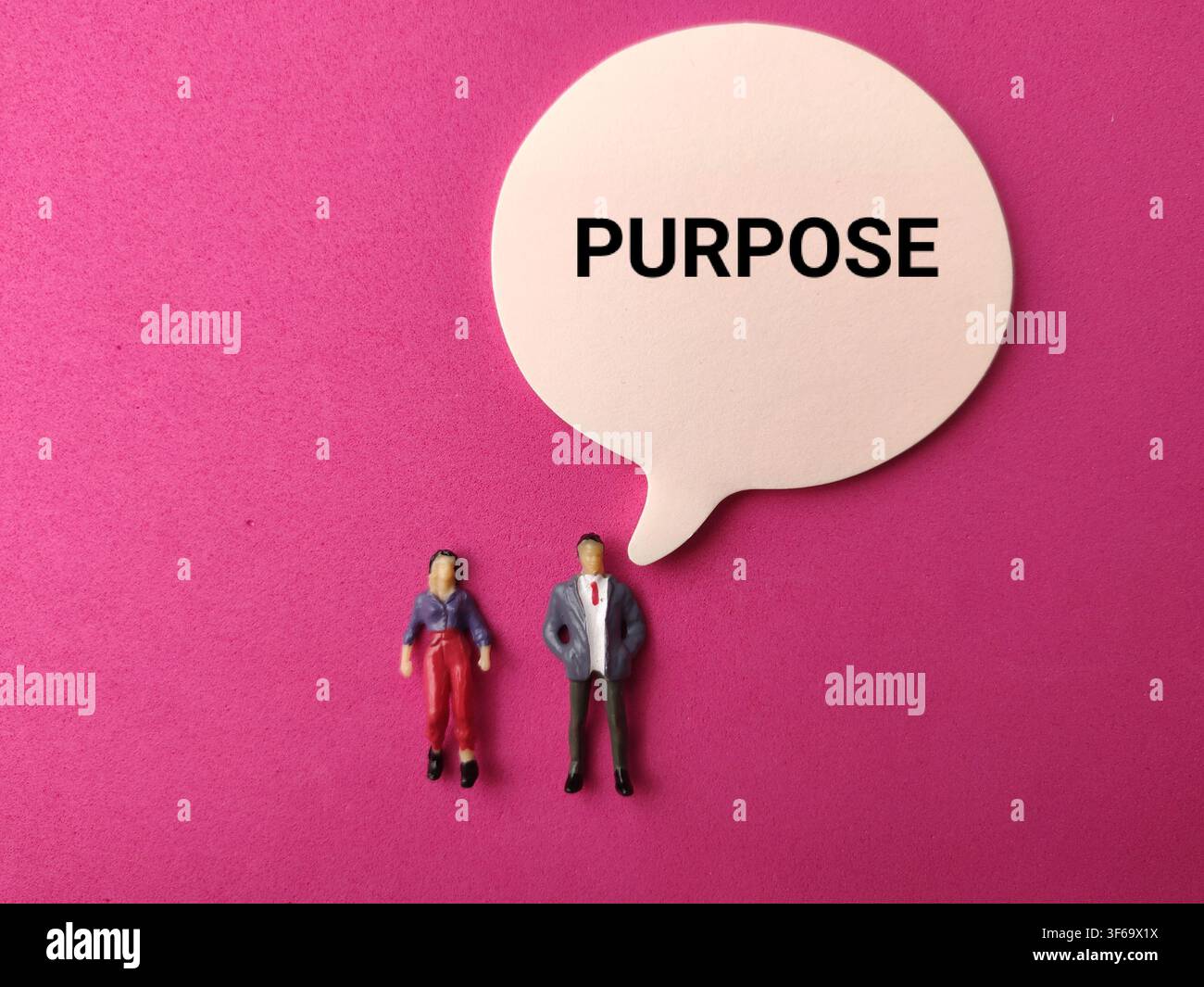 Des figurines humaines miniatures se tiennent sous une bulle de dialogue imprimée avec le mot BUT sur un fond rose. Banque D'Images