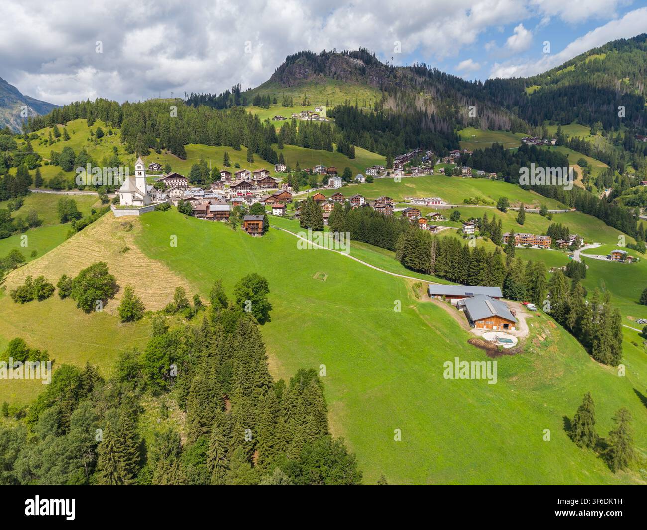 Vue aérienne du village alpin niché dans les pentes verdoyantes des Dolomites avec des maisons traditionnelles et une église historique à Colle Santa Lucia Banque D'Images