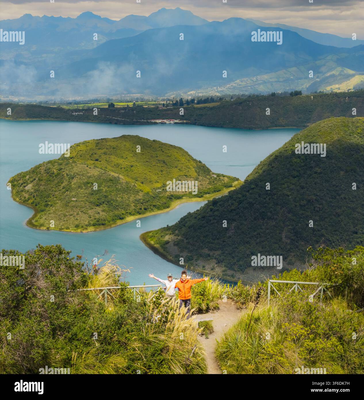 Vue aérienne de la Laguna de Cuicocha avec ses îles, entourée de collines et montagnes luxuriantes, avec deux personnes debout sur un point de vue à Cotacachi Banque D'Images