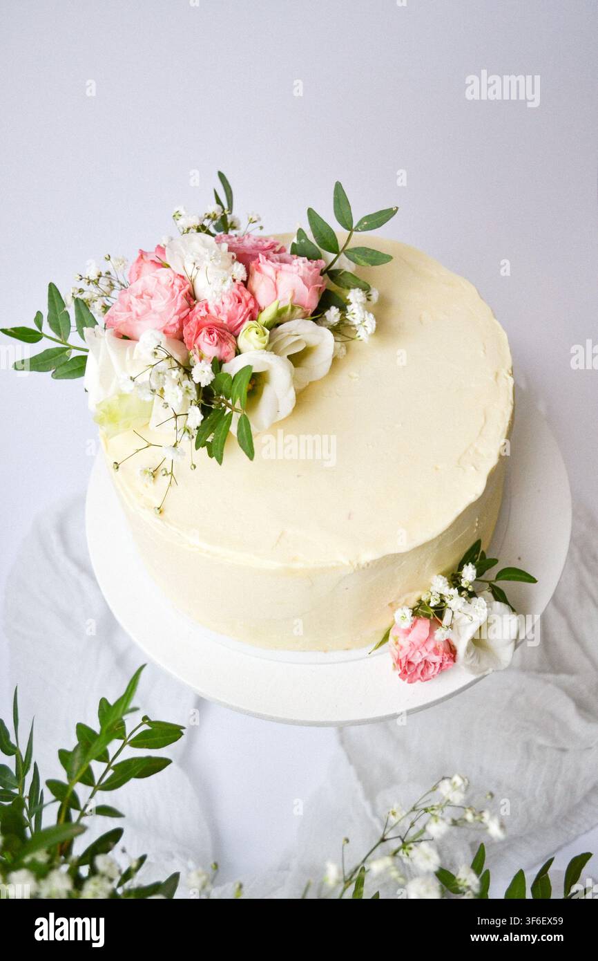 Gâteau blanc givré élégant décoré d'un bouquet de fleurs fraîches roses et blanches Banque D'Images