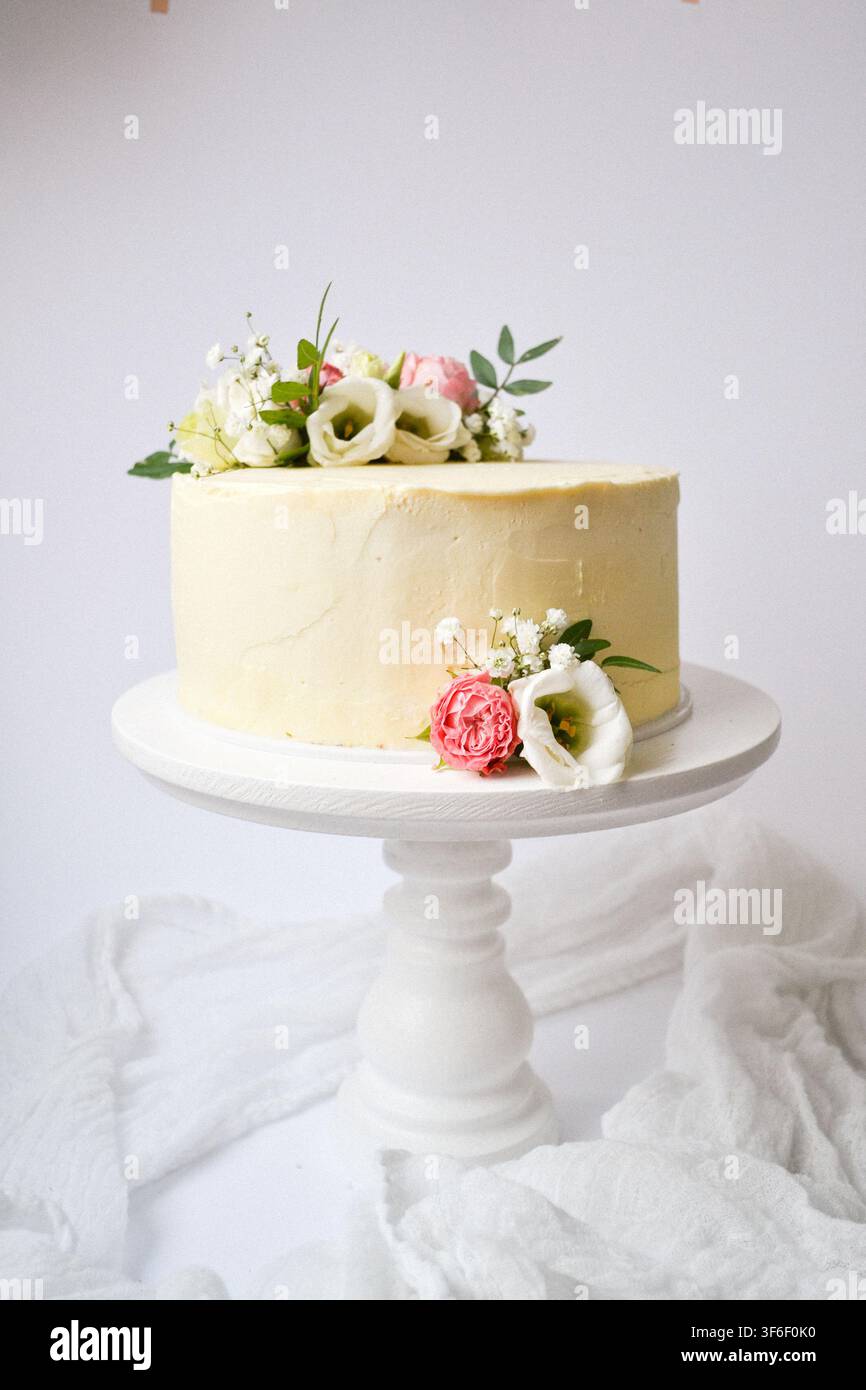 Gâteau de mariage blanc élégant décoré de fleurs d'eustoma fraîches et de gypsophile sur un support en bois Banque D'Images