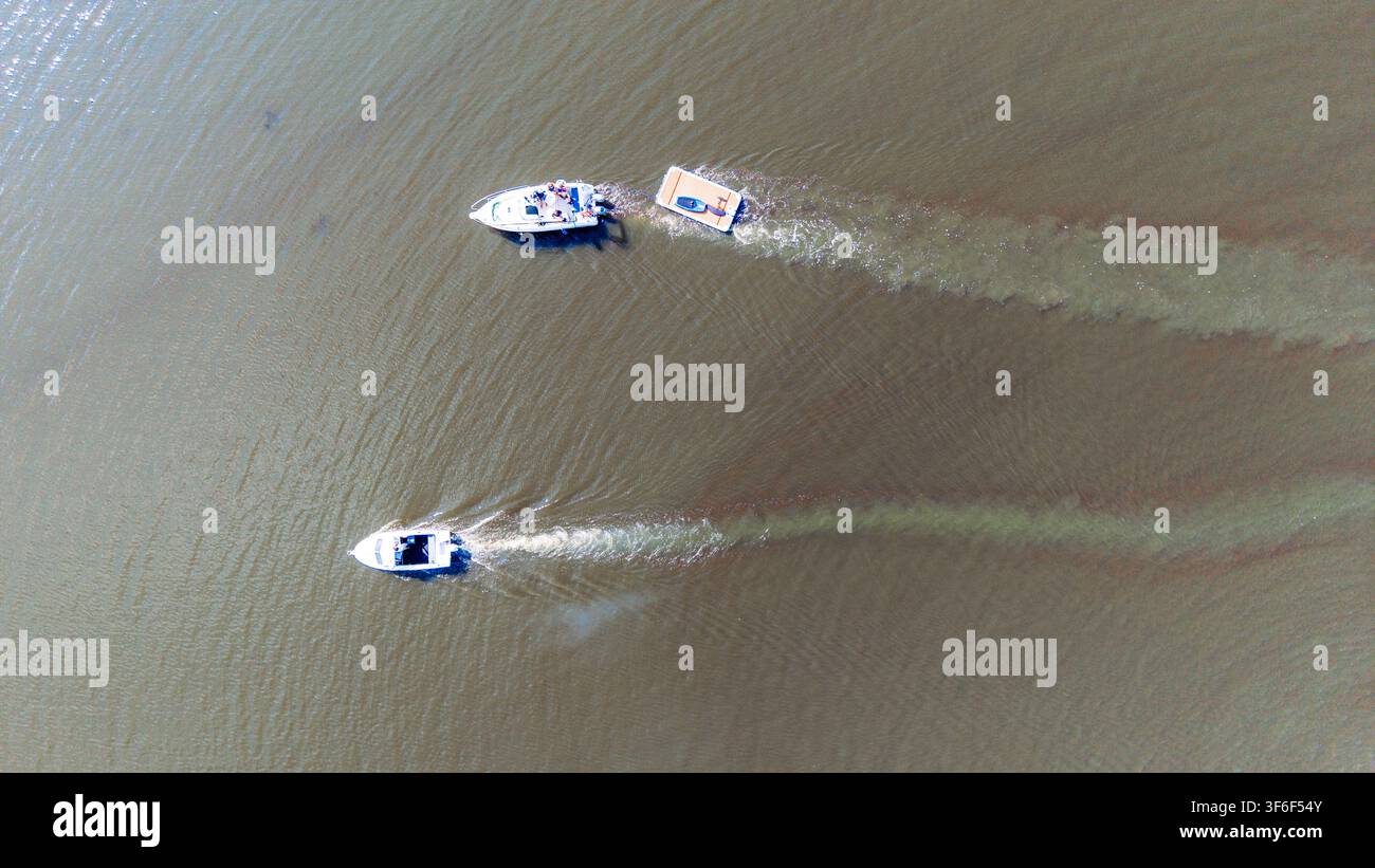 Vue aérienne de dessus de deux bateaux à moteur naviguant sur l'eau en laissant de longues rides Banque D'Images