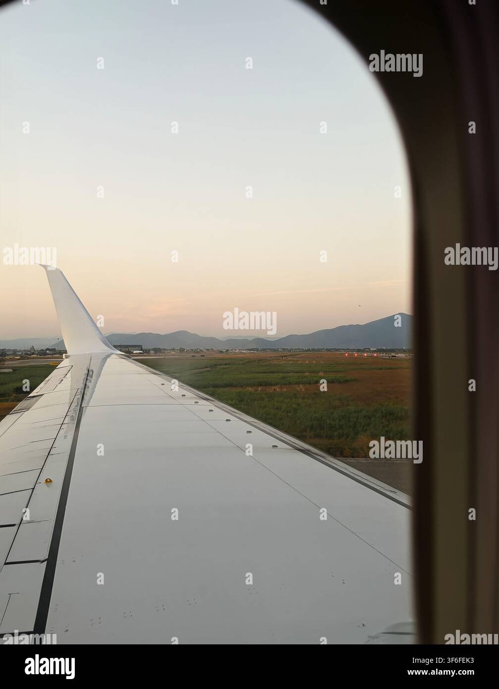 Vue depuis une fenêtre d'avion avec l'aile au coucher du soleil avant le décollage, capturant l'atmosphère de voyage, d'aviation et de voyage estival. Banque D'Images