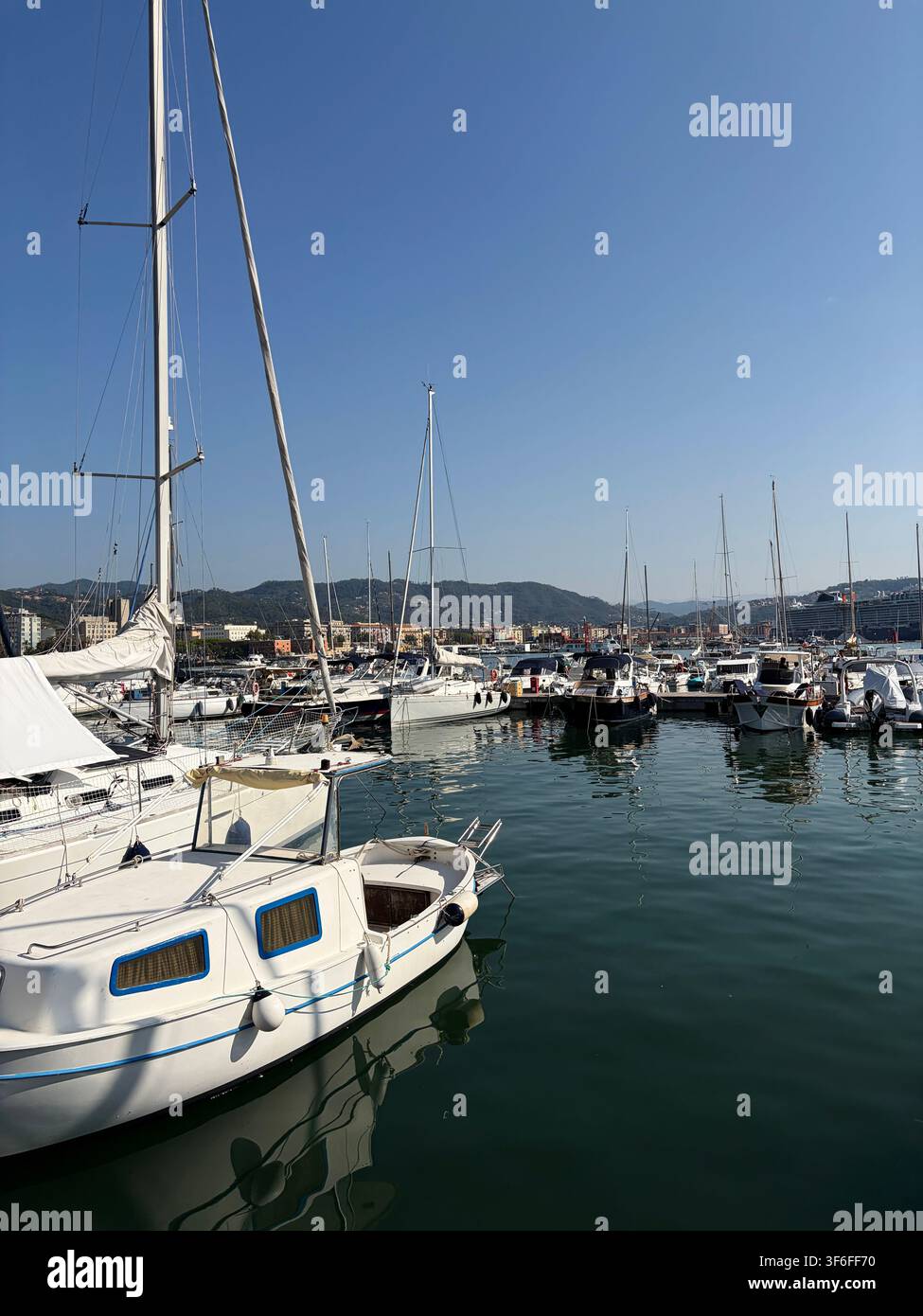 Des voiliers et des yachts blancs amarrés dans une marina méditerranéenne par une journée ensoleillée avec une eau calme et un ciel bleu clair. Banque D'Images