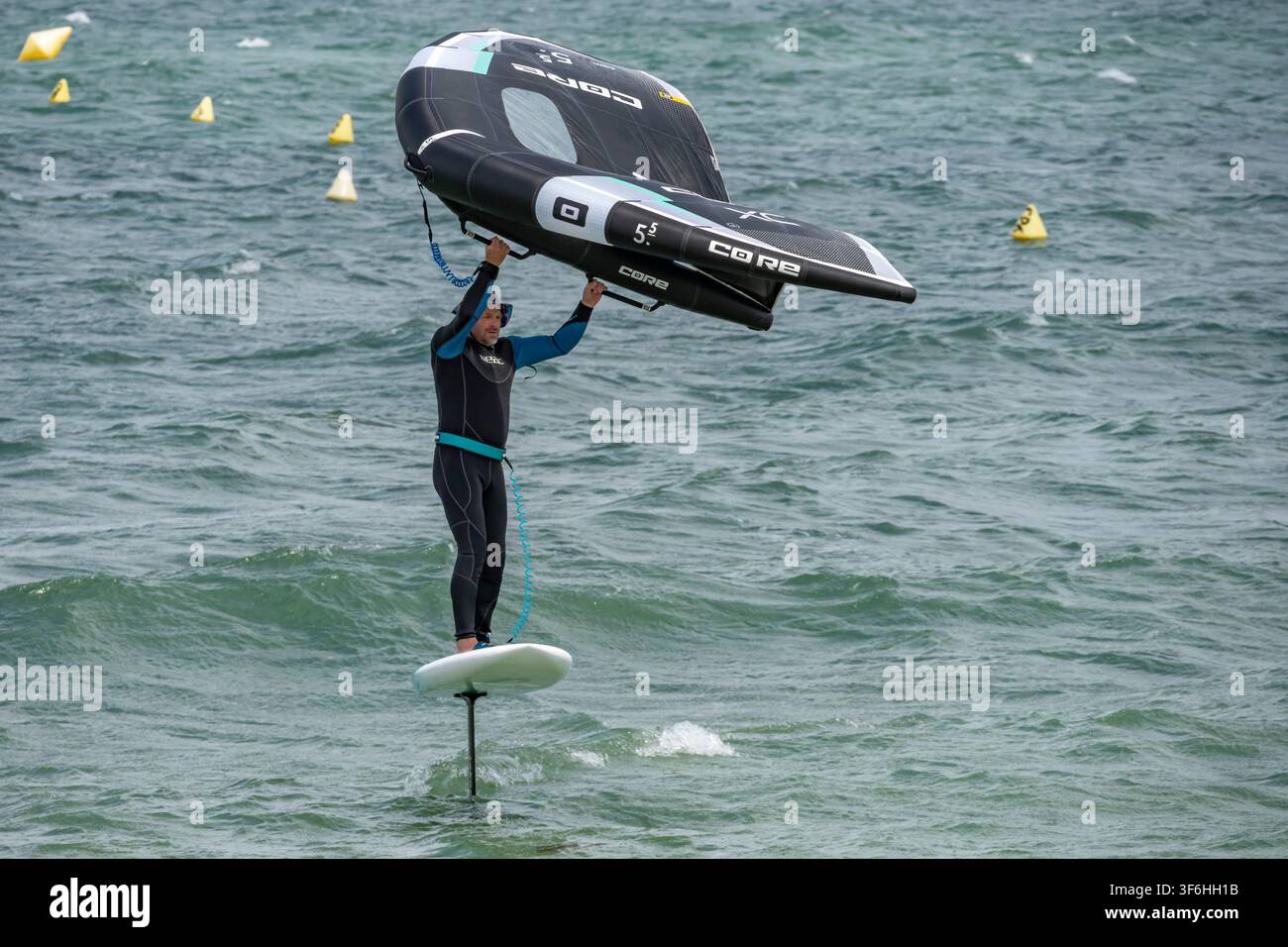 Langrune-Sur-Mer, France - 08 05 2026 : Un planchiste portant une combinaison de plongée surfe avec un wingsurf sur la mer Banque D'Images