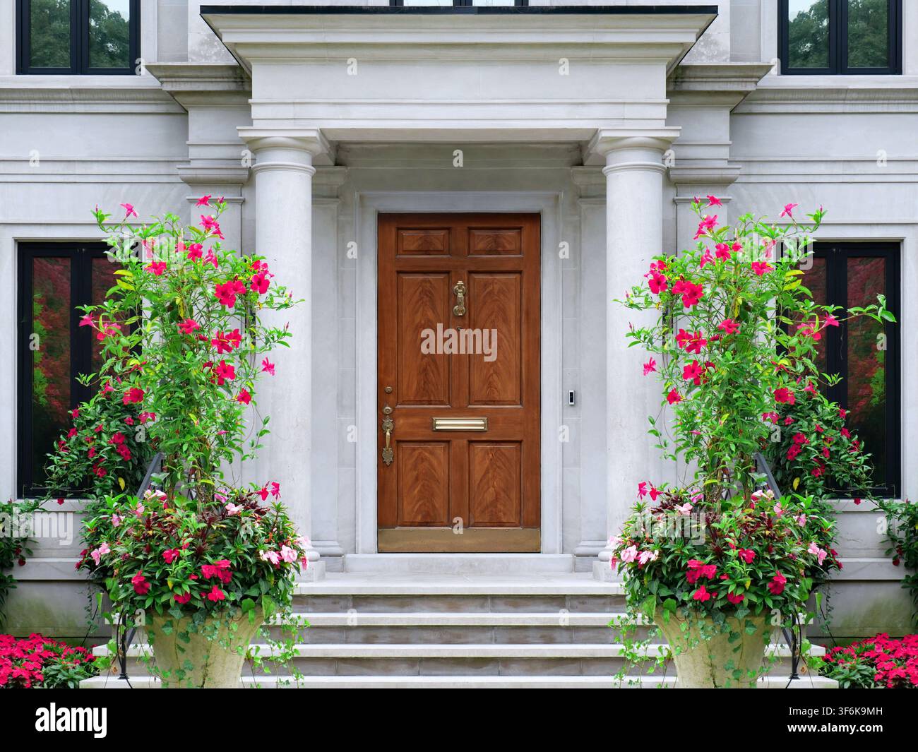 Entrée de maison avec colonnes en pierre et grands pots de vignes fleuries de Mandevilla Banque D'Images