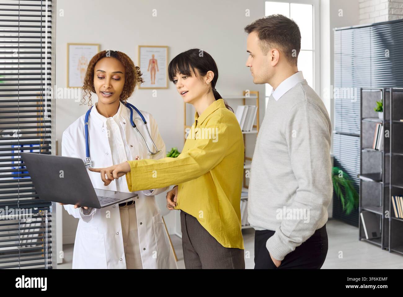 Couple examinant les résultats avec un médecin en utilisant un ordinateur portable lors d'une consultation de planification de la fertilité Banque D'Images