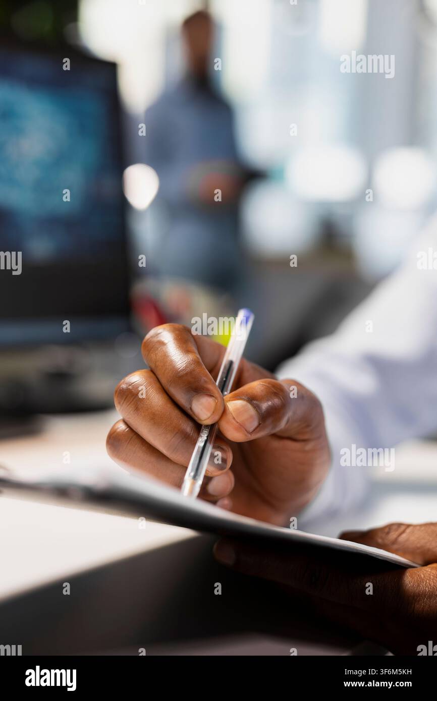 Gros plan d'un employé de bureau remplissant des documents administratifs sur un tableau à pince à bureau, aidé par un logiciel d'IA. Le travailleur gère les tâches de documentation à l'aide d'outils d'intelligence artificielle pour le soutien et la précision Banque D'Images