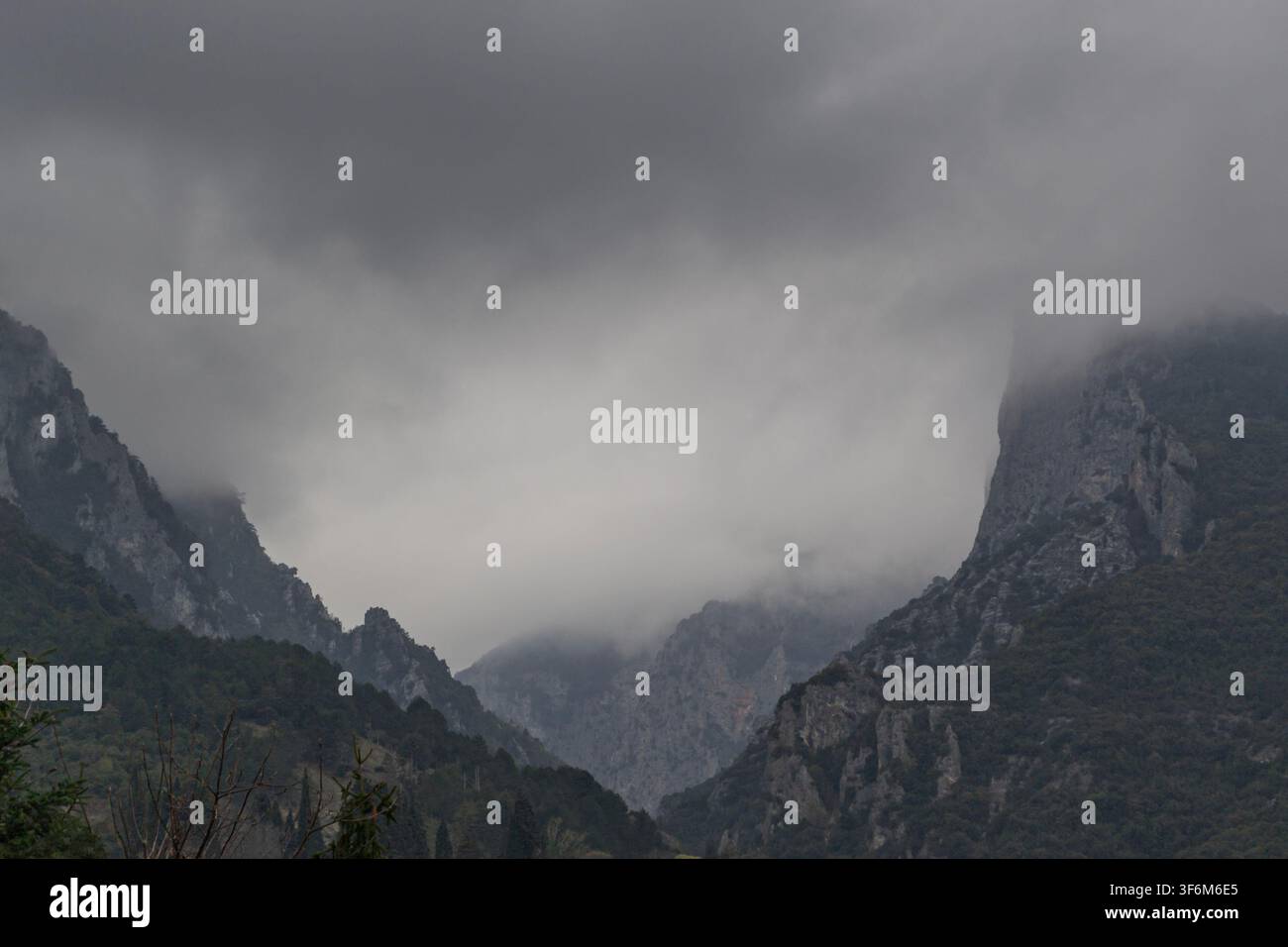 Gorge montagneuse brumeuse sous un ciel nuageux dramatique Banque D'Images