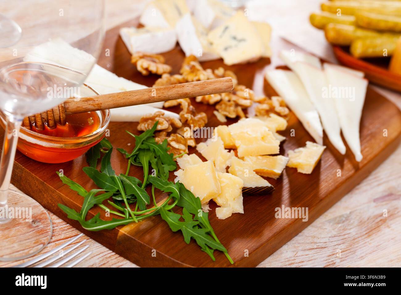 Différents types de fromage servis sur bois avec du miel, des tranches de noix Banque D'Images