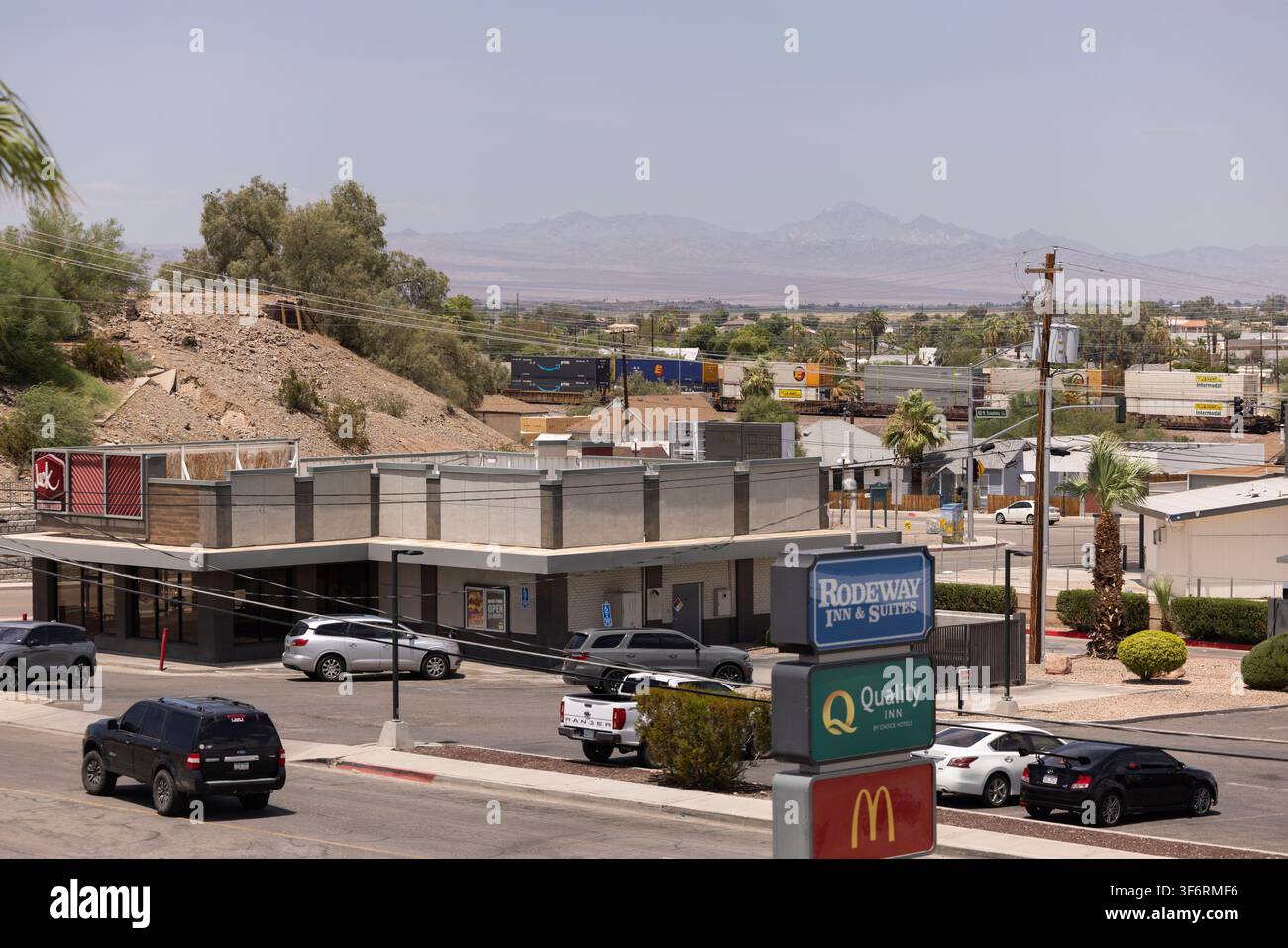 Needles, Californie, États-Unis - 28 juillet 2026 : Le trafic automobile et ferroviaire de marchandises de l'après-midi traverse le centre-ville. Banque D'Images