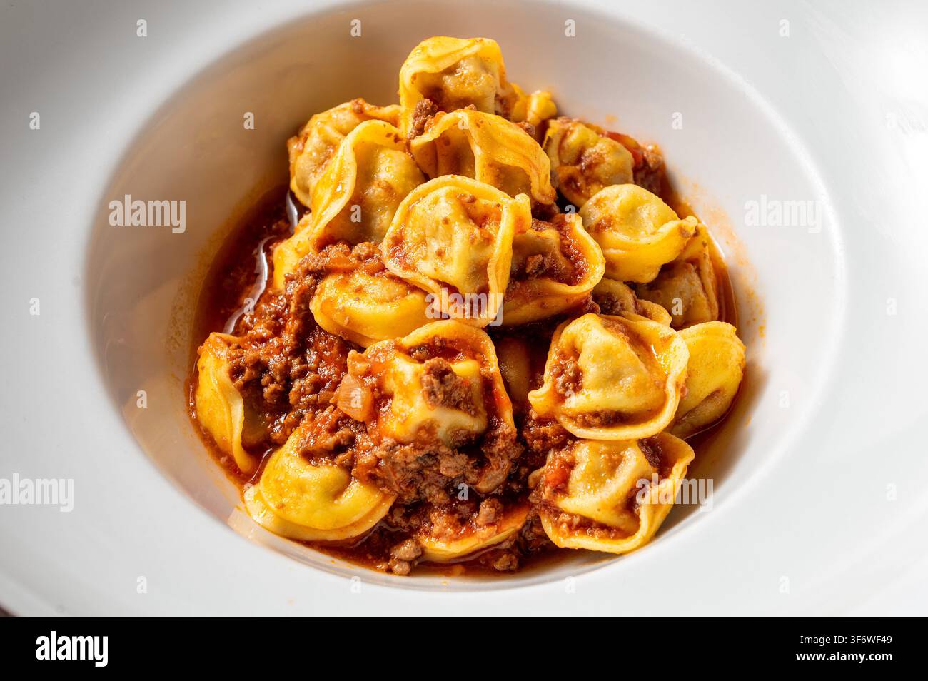 Tortellini italiennes servi avec une riche ragù de bœuf et une sauce tomate, présenté dans un bol en céramique blanche. Plat de pâtes fait maison traditionnel d'Italie centrale. Banque D'Images