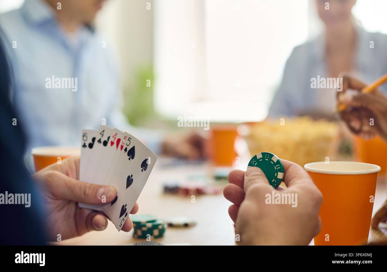 Amis jouant au poker, gros plan sur les mains avec des cartes et des jetons sur la table à l'intérieur Banque D'Images