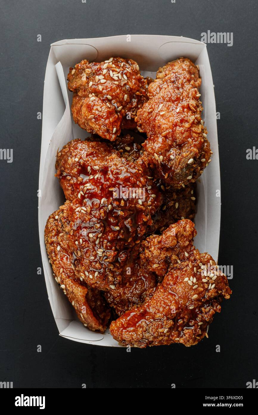 Ailes de poulet frites et croustillantes au sésame sur un fond noir Banque D'Images
