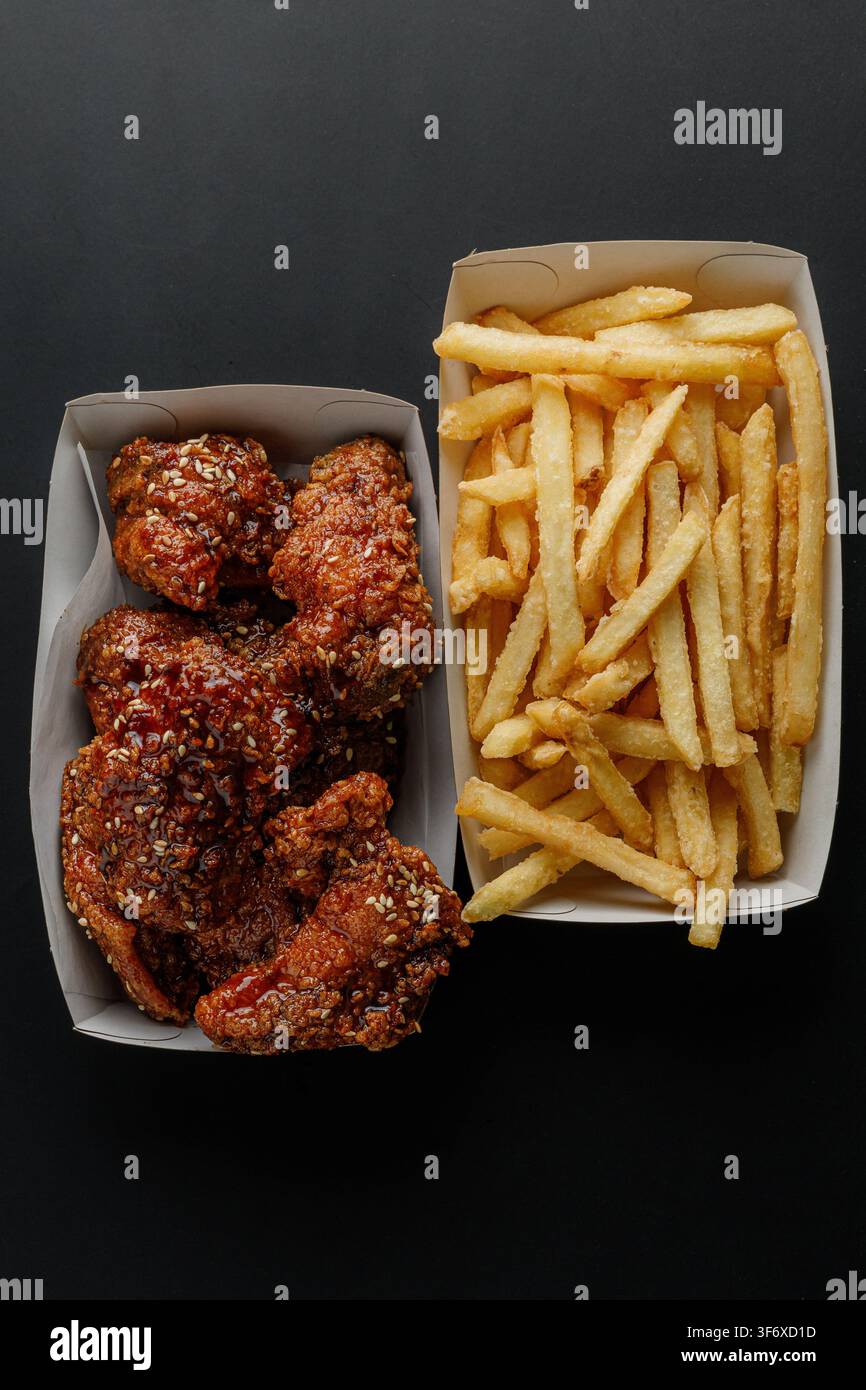 Vue de dessus de poulet frit et frites sur fond noir Banque D'Images