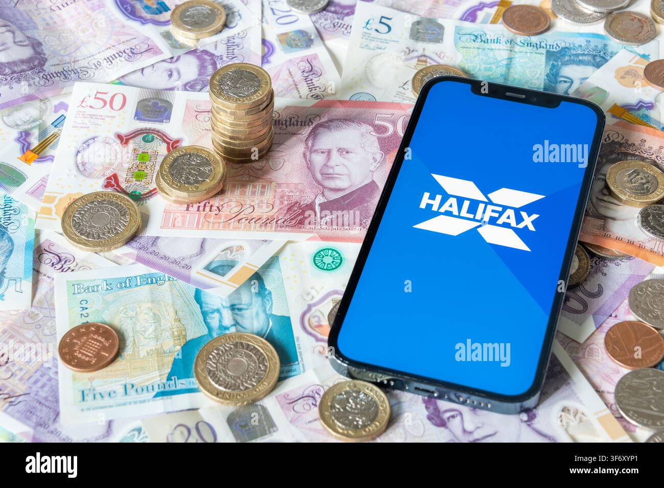 Application de banque Halifax avec des billets et pièces en livres sterling en arrière-plan Banque D'Images