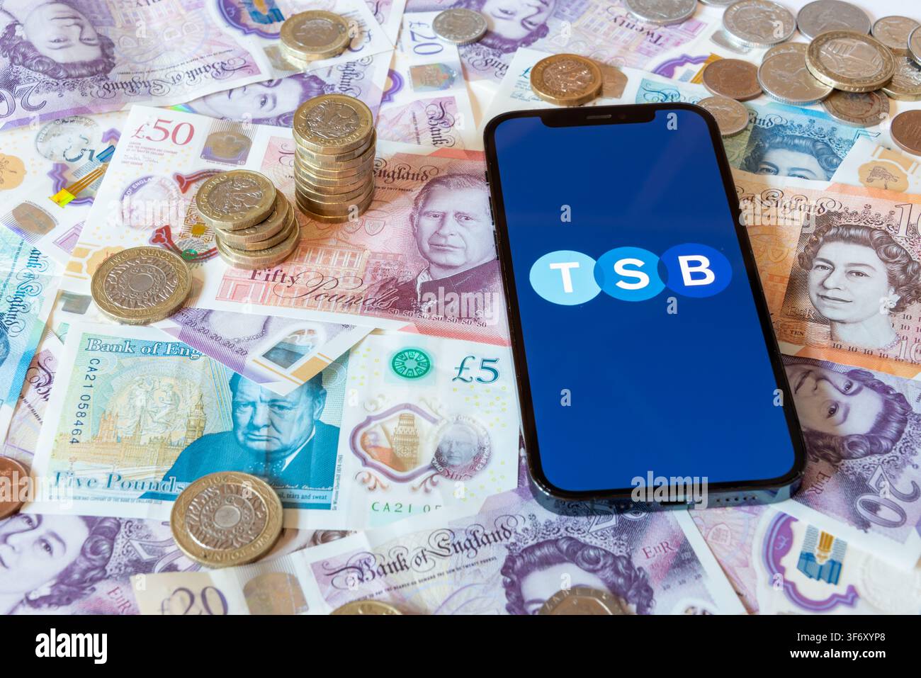 Application bancaire TSB Bank avec des billets et pièces en livres sterling en arrière-plan Banque D'Images