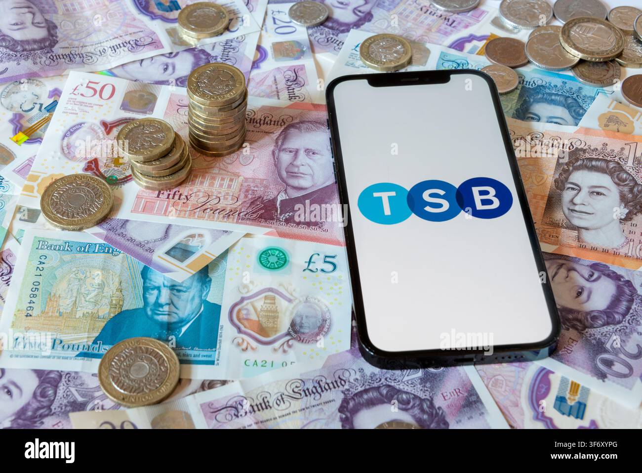 Application bancaire TSB Bank avec des billets et pièces en livres sterling en arrière-plan Banque D'Images