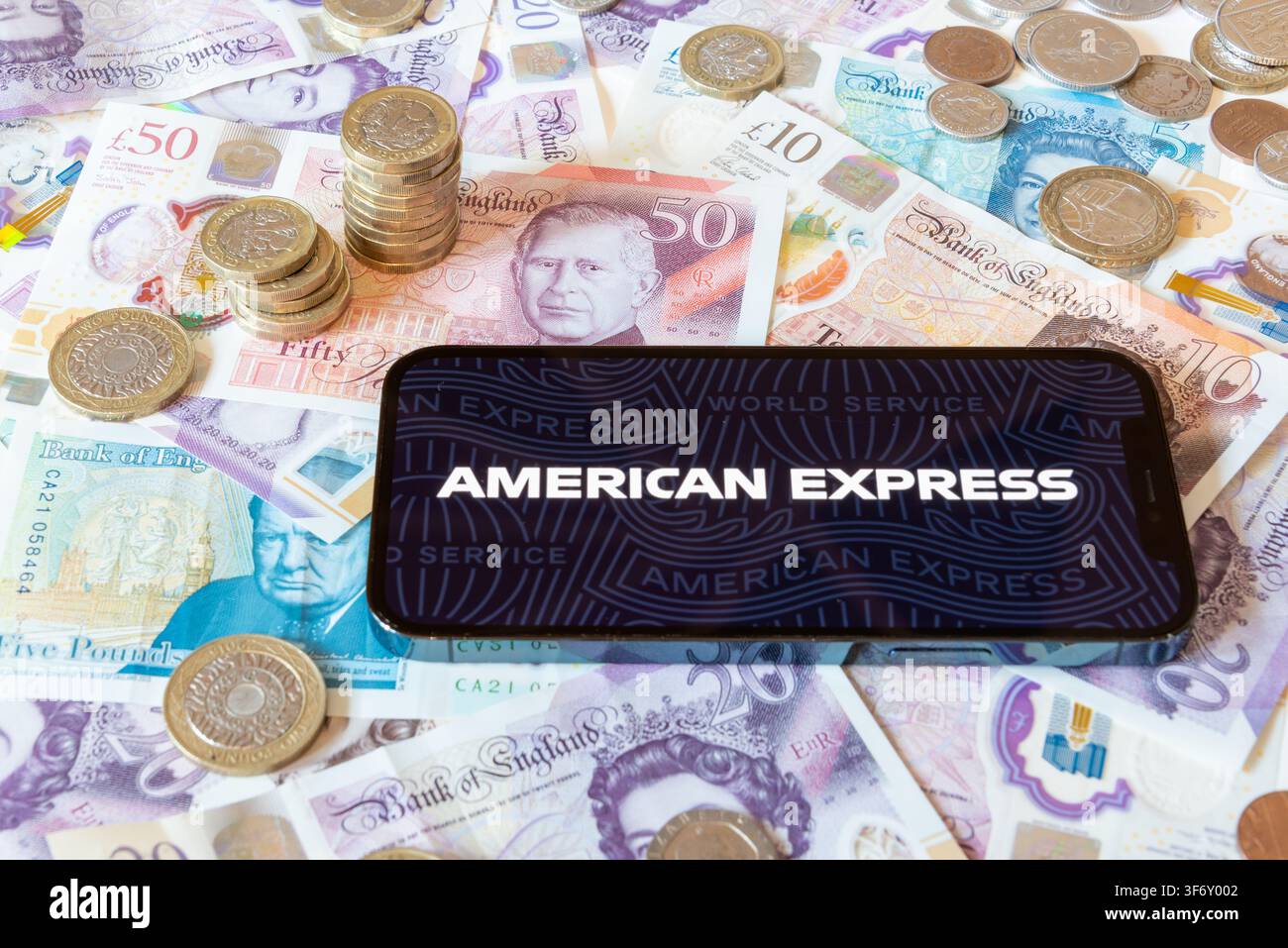 Application bancaire American Express avec des billets et pièces en livres en arrière-plan Banque D'Images