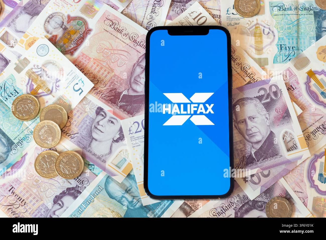 Application de banque Halifax avec des billets et pièces en livres sterling en arrière-plan Banque D'Images