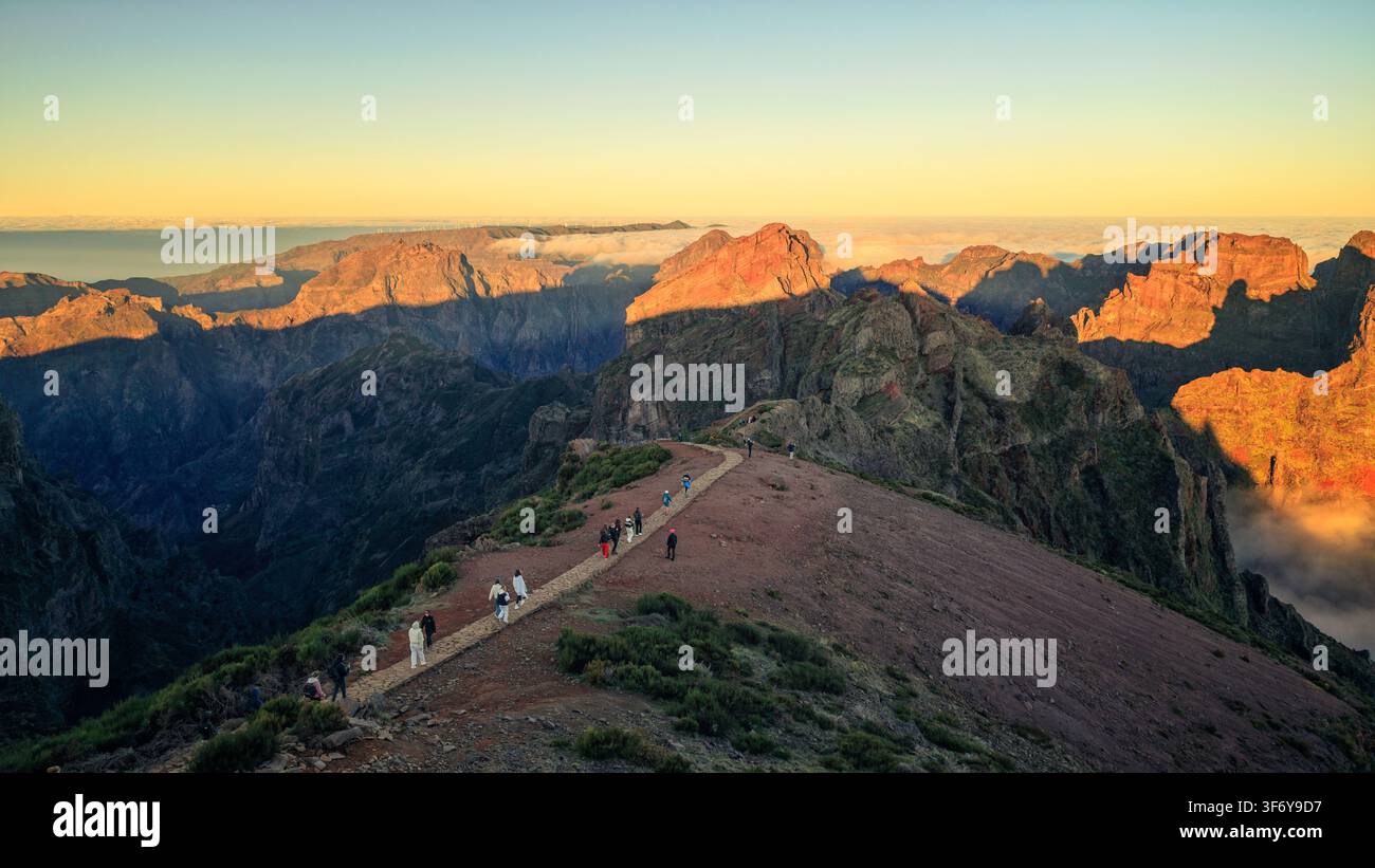 Juncal, Portugal - 05.12.2025 : Vue panoramique de trekkeurs traversant une crête rocheuse pendant le coucher du soleil avec des ombres dramatiques et des nuages bas Banque D'Images