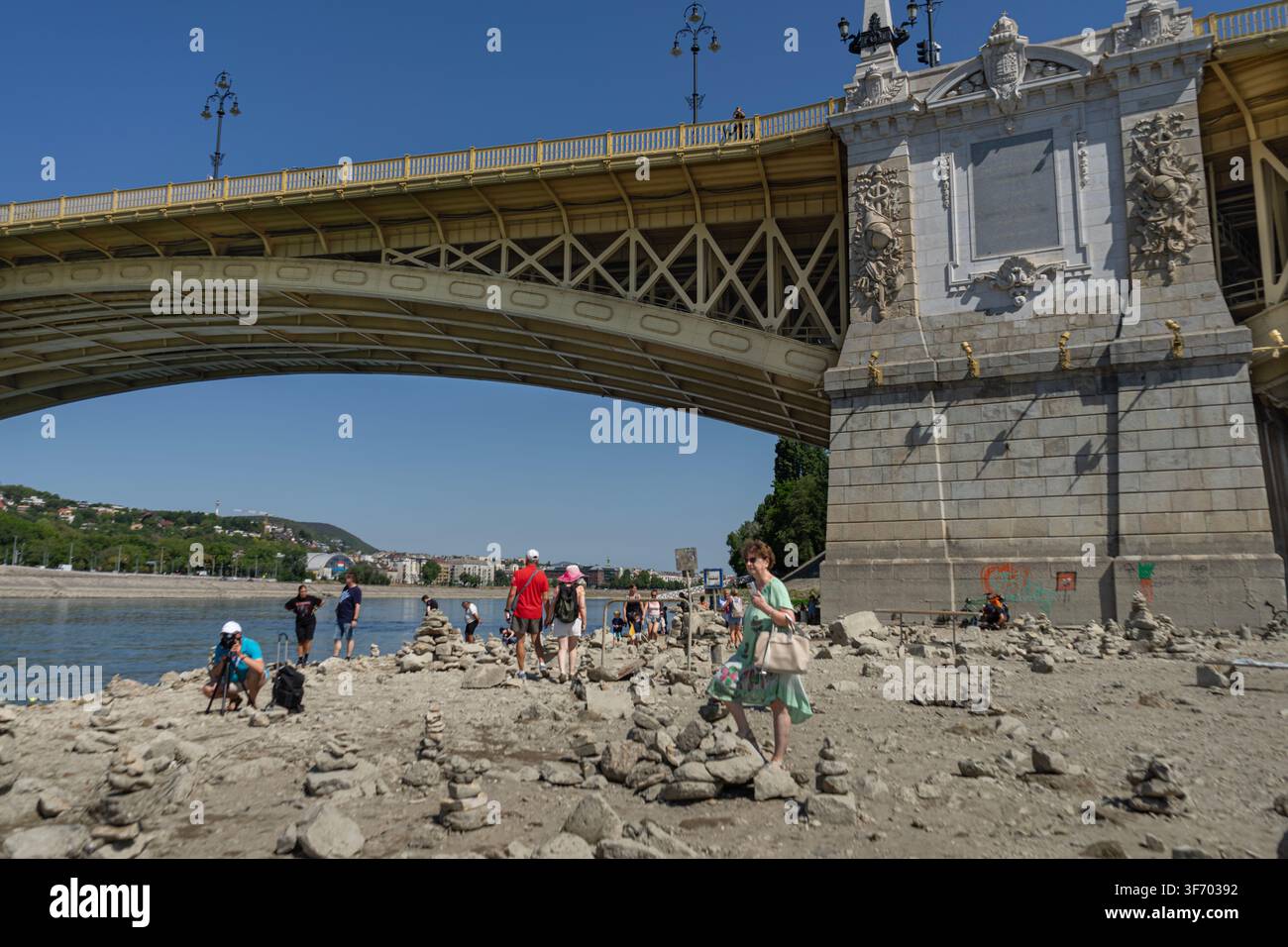 Les gens explorent le lit rocheux exposé sous le pont Margaret alors que le Danube chute à des niveaux d'eau exceptionnellement bas à Budapest. Banque D'Images