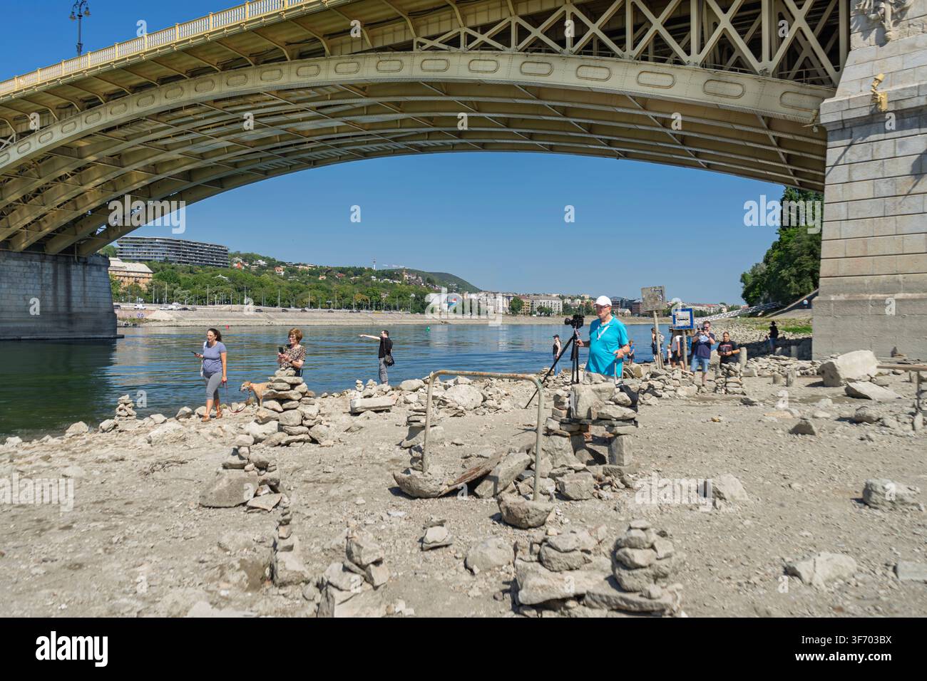 Les gens explorent le lit rocheux exposé sous le pont Margaret alors que le Danube chute à des niveaux d'eau exceptionnellement bas à Budapest. Banque D'Images