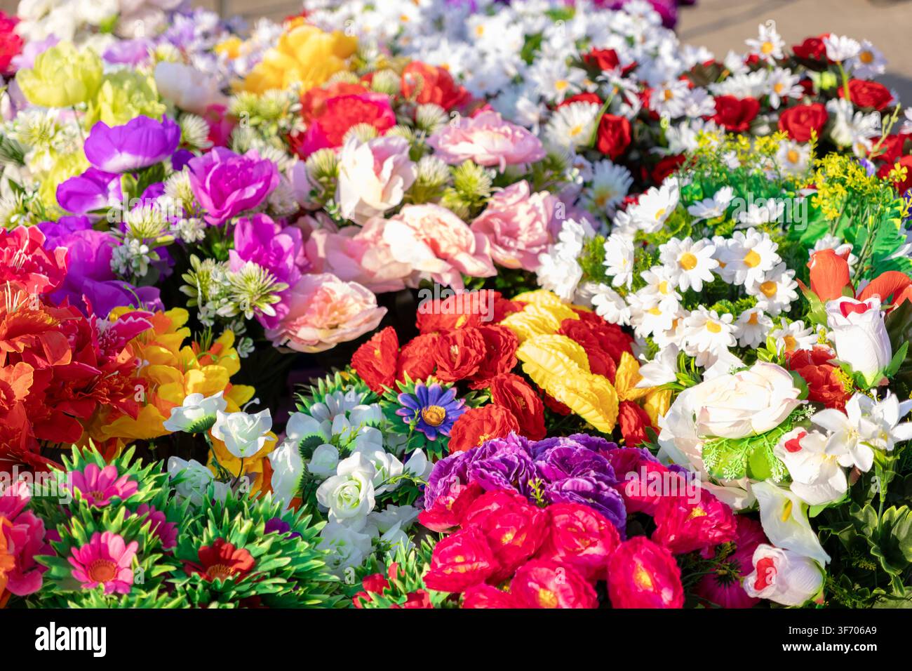 Une vue rapprochée de fleurs en soie synthétique assorties dans diverses teintes brillantes forme un affichage floral texturé adapté aux occasions joyeuses et créat Banque D'Images