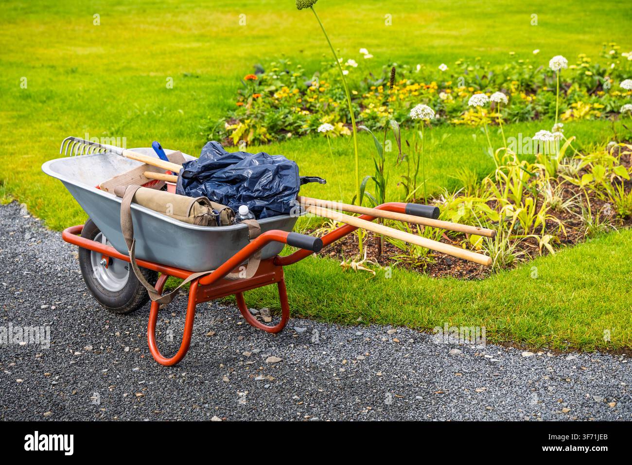 Outils de jardinage dans une brouette prêts pour le travail de cour par une journée ensoleillée Banque D'Images
