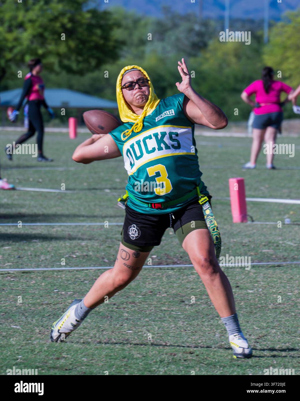 Mai 2023 : Un joueur de flag football portant un maillot à capuche se prépare à lancer le ballon sur un terrain en herbe pendant une partie. Banque D'Images