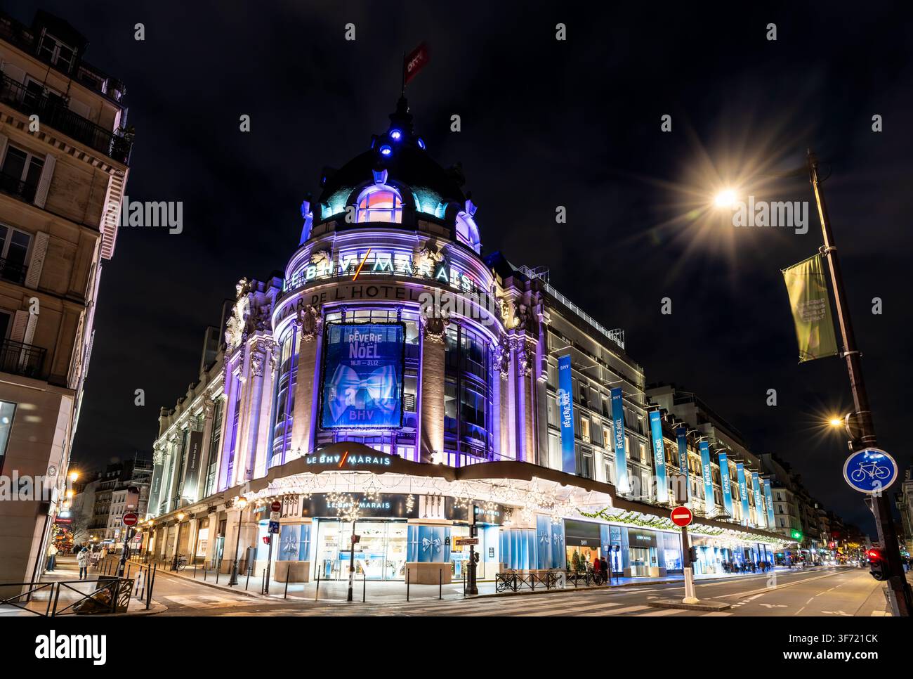 Paris, France – 24 décembre 2025 : Vue extérieure du grand magasin Le BHV Marais décoré de lumières festives la nuit. Banque D'Images