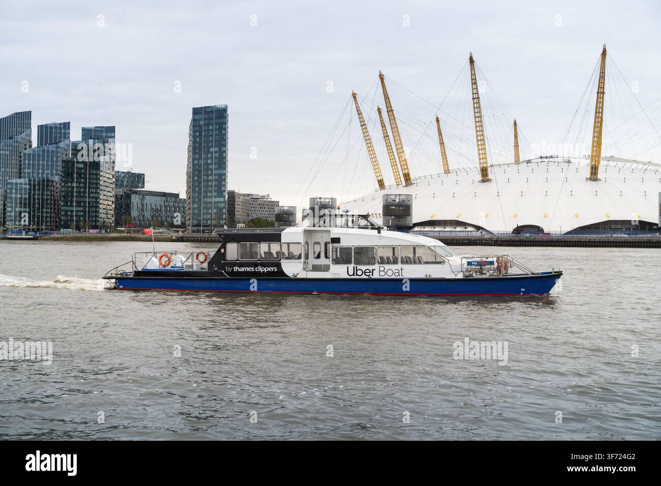 Un bateau Uber par Thames Clippers transporte les passagers le long de la Tamise, en passant devant l'emblématique O2 Arena de Londres. Banque D'Images