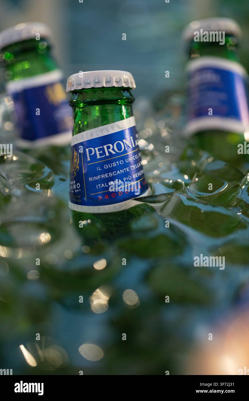 Des bouteilles rafraîchissantes de Peroni Nastro Azzurro refroidissent dans un bain de glace, préparant cette bière lager italienne pétillante de Rome à être servie froide. Banque D'Images