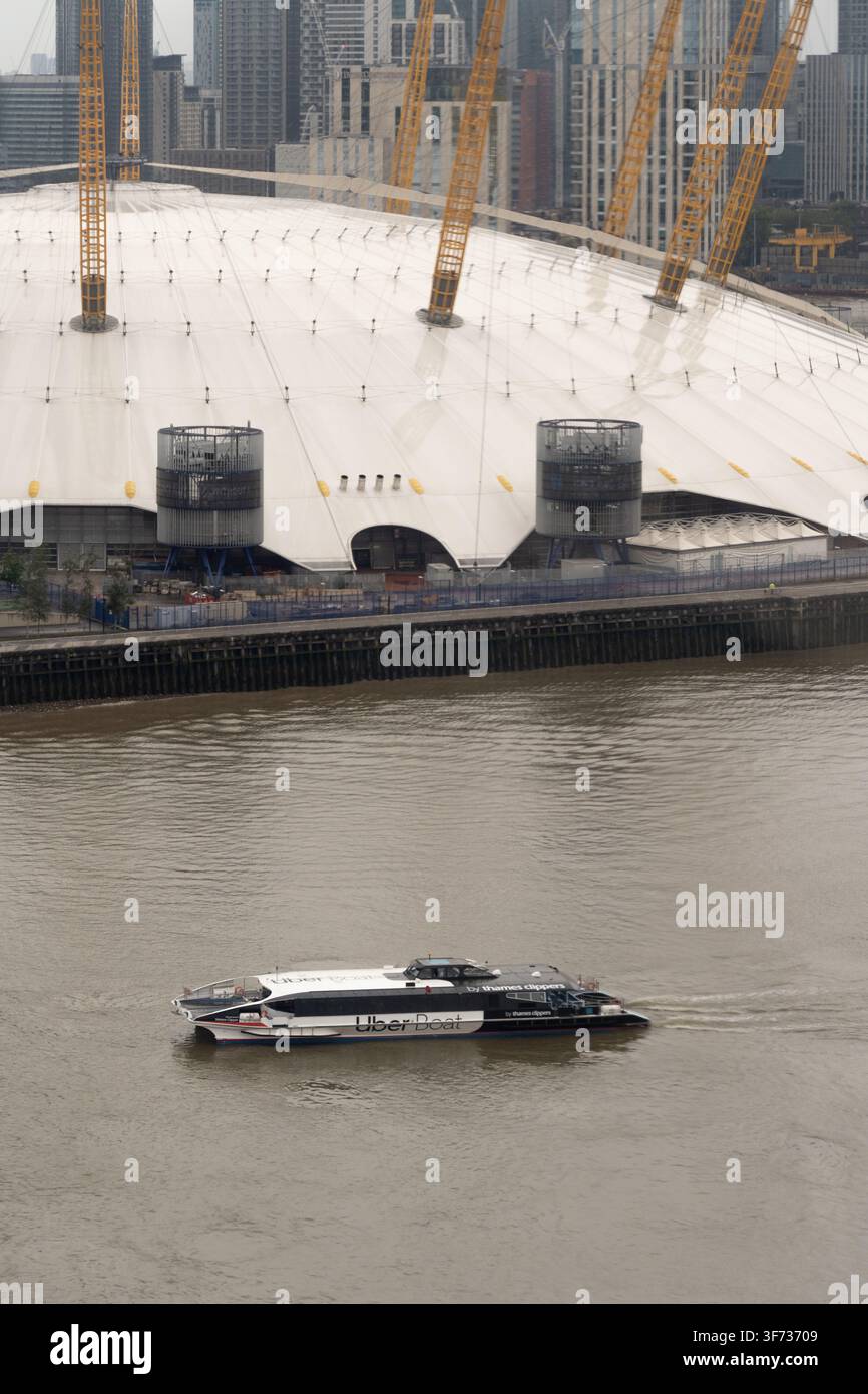 Un Uber Boat de Thames Clippers transporte des passagers le long de la Tamise à Londres, passant devant l'emblématique O2 Arena à Greenwich. Banque D'Images
