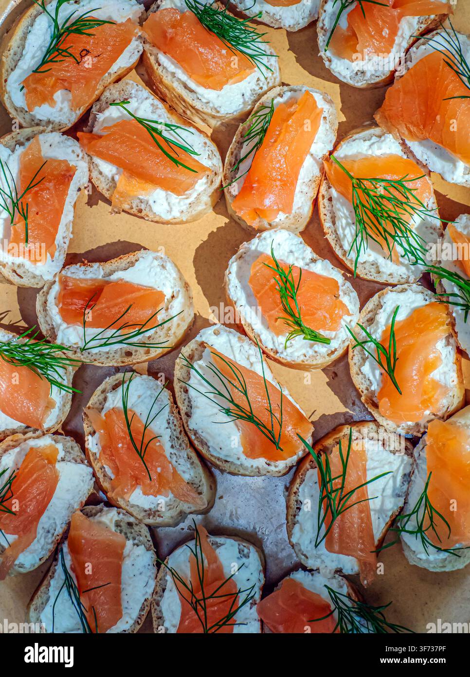 Canapés au saumon fumé disposés sur des tranches de baguette rustique garnies de fromage frais et d'aneth frais, des hors-d'œuvre savoureux et lumineux parfaits pour les fêtes, le brunch Banque D'Images
