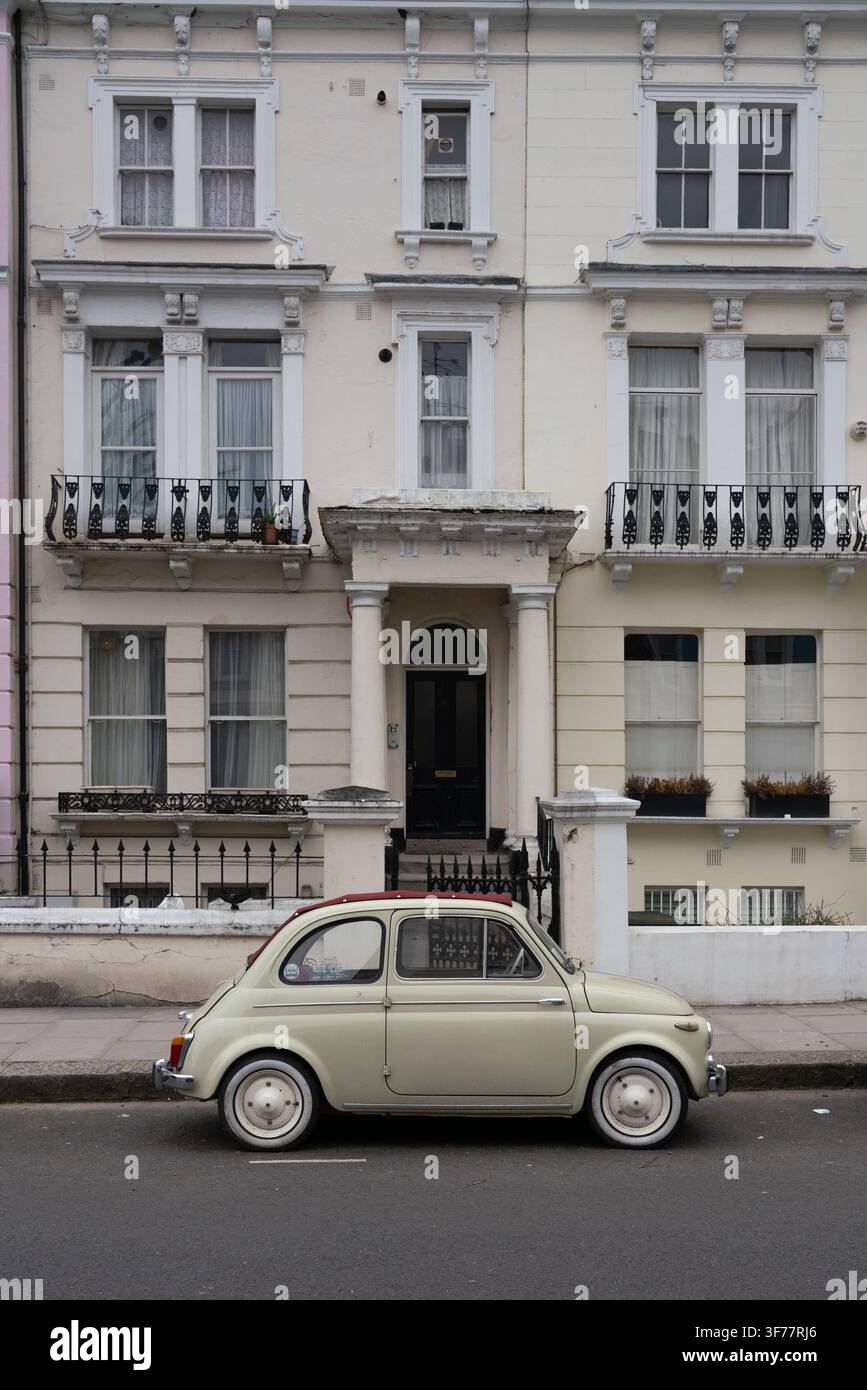 Une Fiat 500 vintage garée devant une maison victorienne en stuc blanc sur Elgin Crescent, à Notting Hill, capture le charme typique de Londres. Banque D'Images