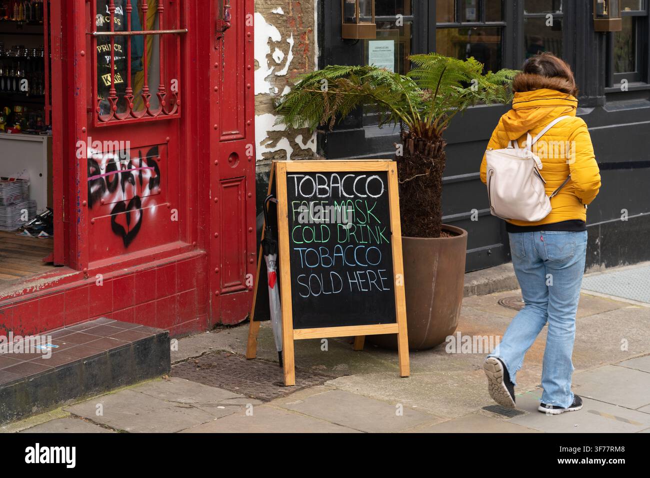 Un piéton passe devant une boutique faisant la promotion de tabac et de masques sur Portobello Road dans le quartier de Notting Hill à Londres. Banque D'Images