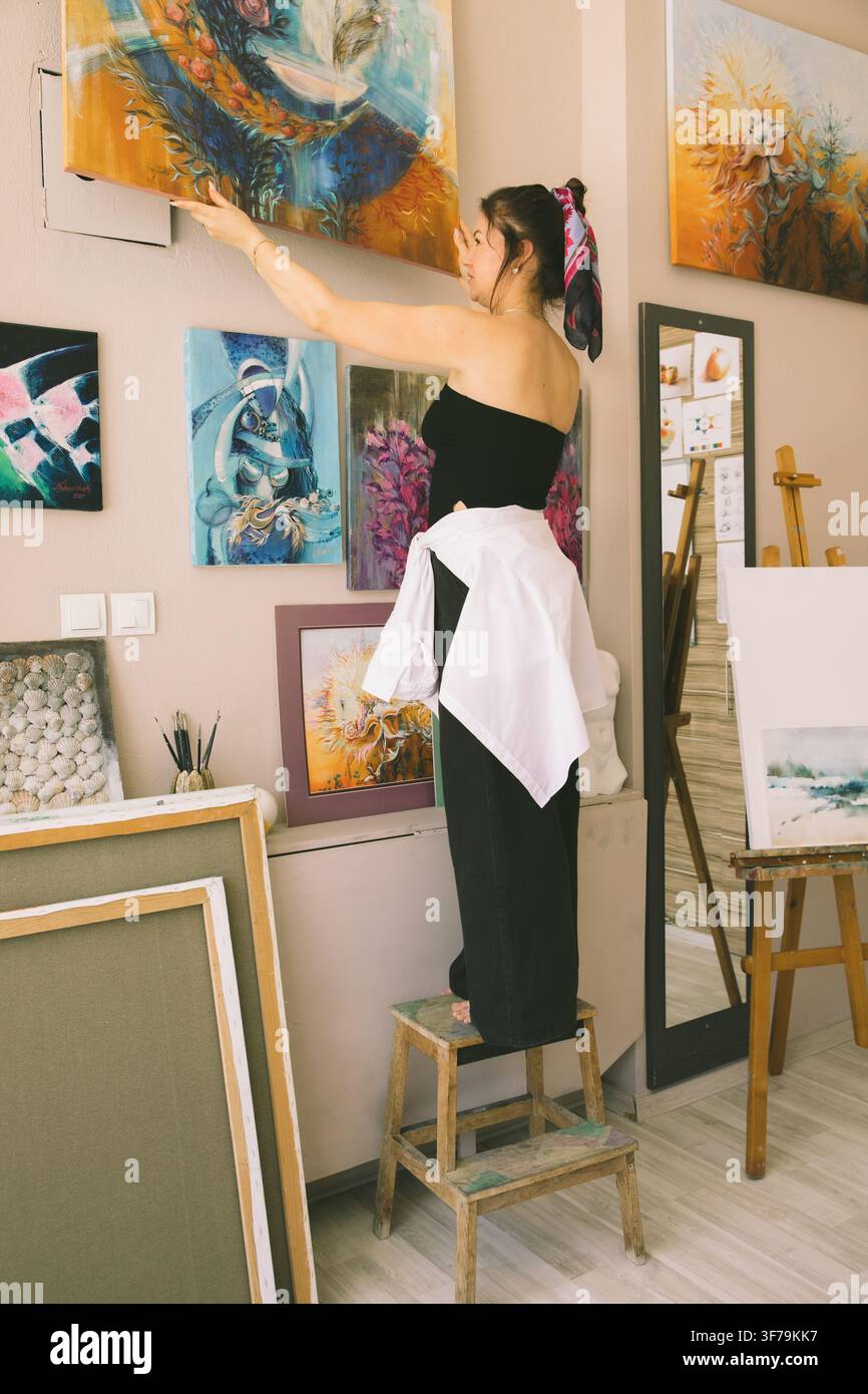 Une artiste féminine arrange ses peintures dans un atelier à domicile, exprimant la créativité par l'art. L'image représente des passe-temps, l'expression de soi, la pleine conscience Banque D'Images