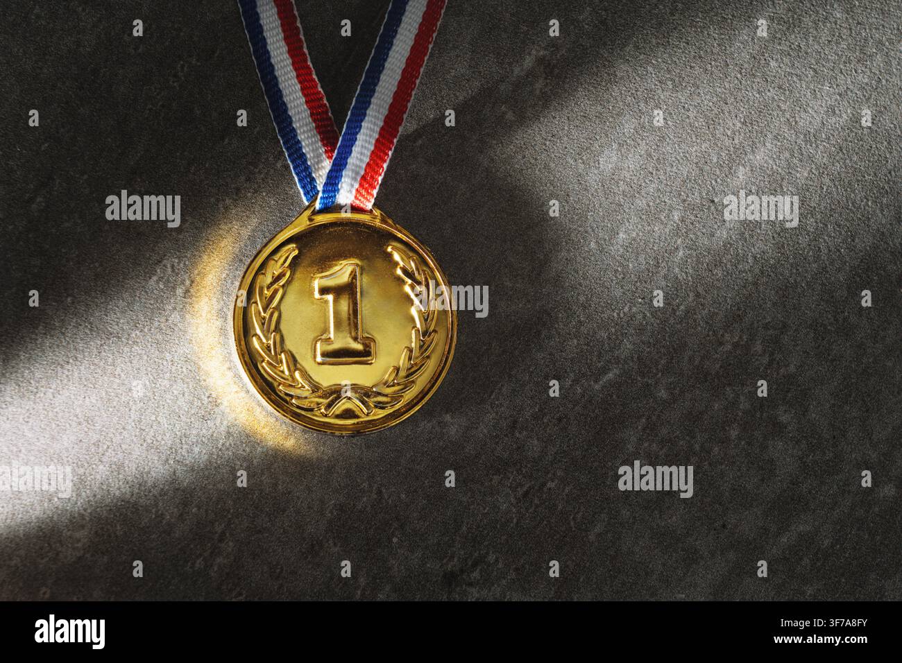 Une médaille d'or réelle isolée sur un fond brut libre avec beaucoup d'espace texte - concept d'espace de copie gagnant Banque D'Images