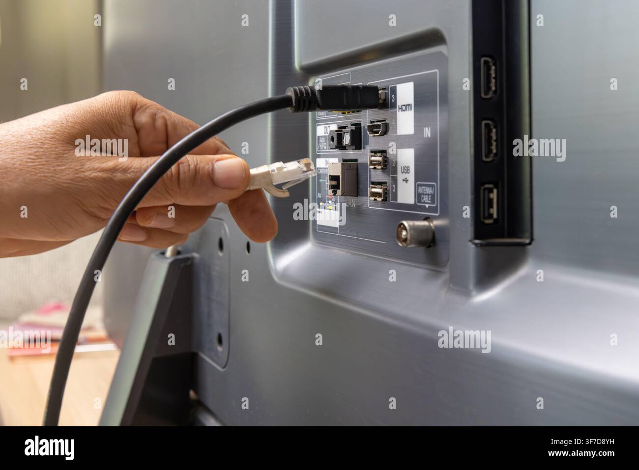 Man connecte le câble Internet au téléviseur. Banque D'Images