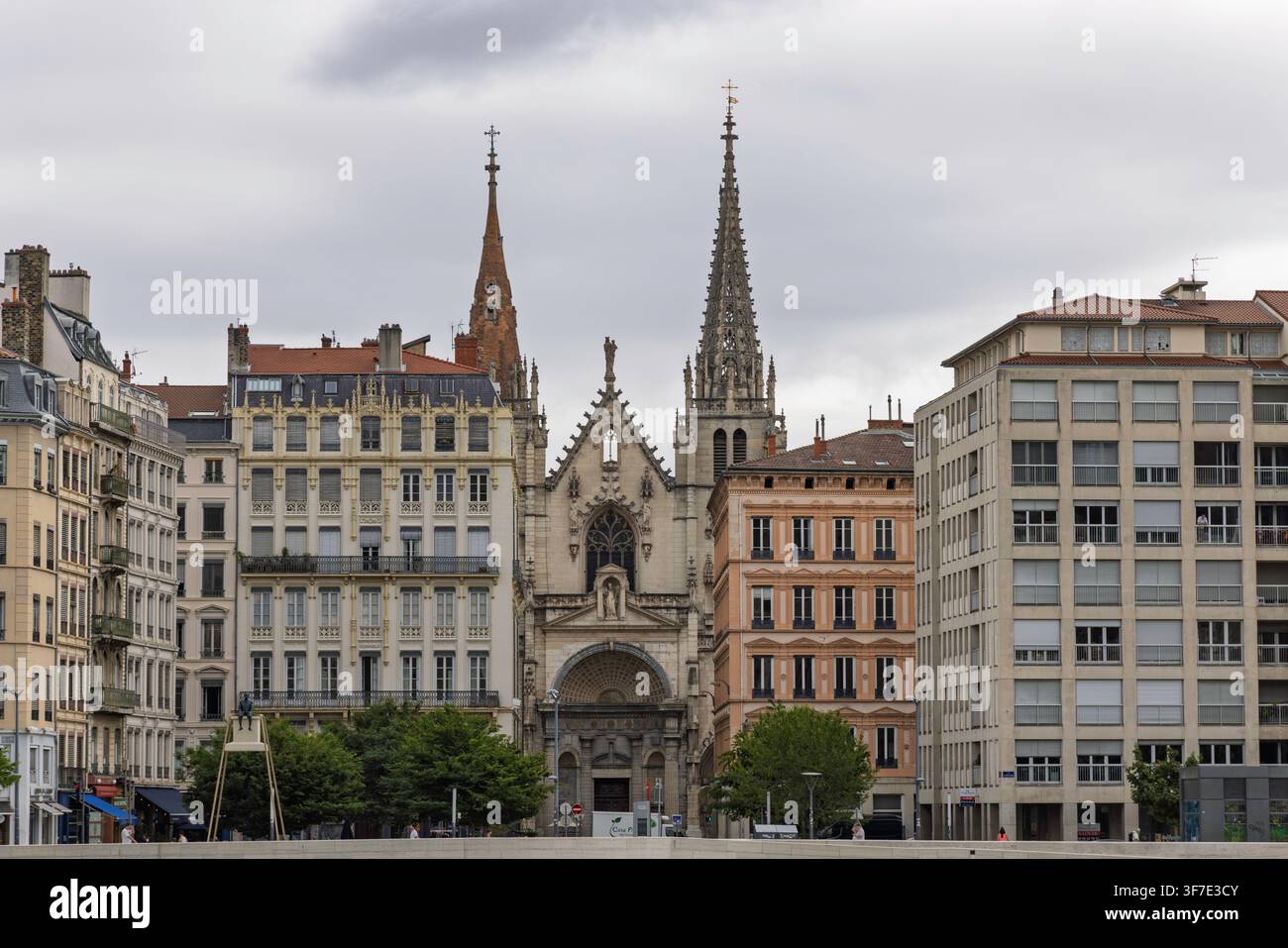 Lyon, France - 27 juillet 2026 : Flèches gothiques et façade de l'église Saint-Nizier entourées de bâtiments historiques sous un ciel nuageux. Banque D'Images